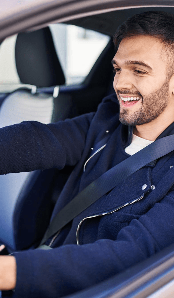 Homem dirigindo um carro e sorrindo